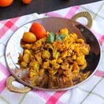 Indian cauliflower stir fry with onion, tomato and spices in a skillet