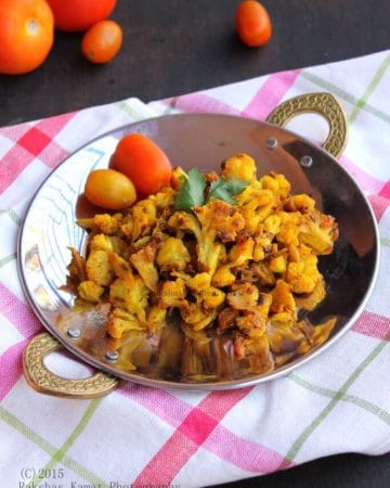 Indian cauliflower stir fry with onion, tomato and spices in a skillet