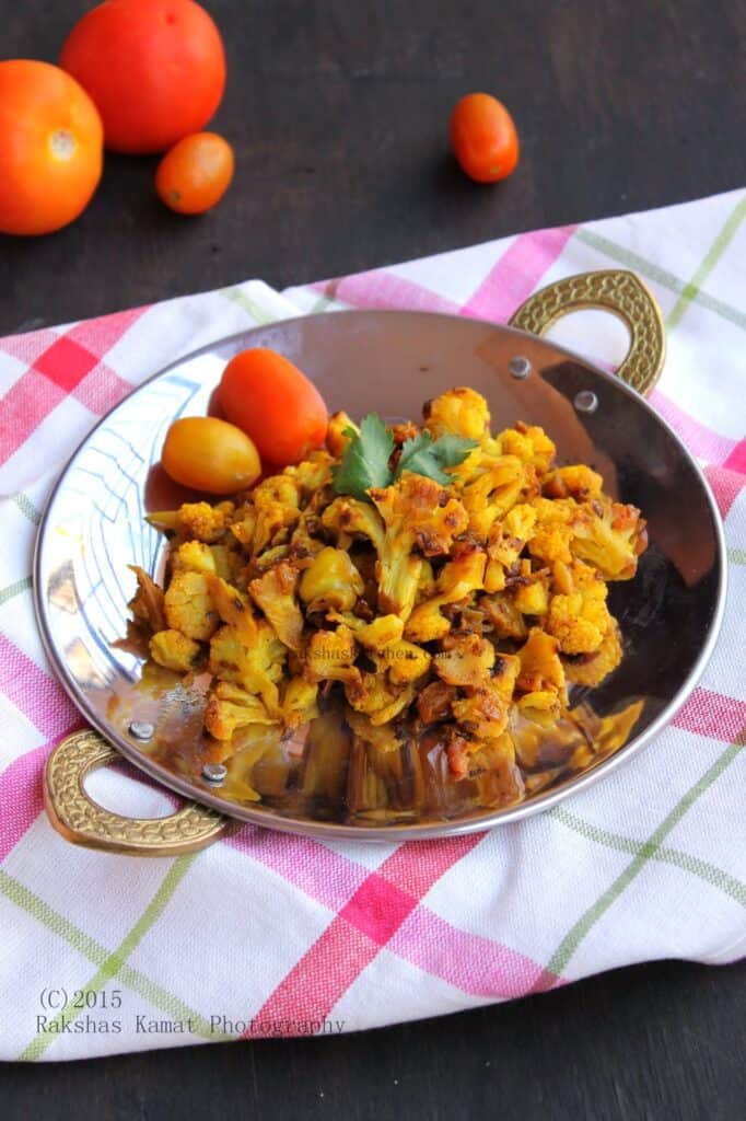 Indian cauliflower stir fry with onion, tomato and spices in a skillet