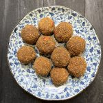 Round moong dal ladoos garnished with crushed cashews and almonds on a plate