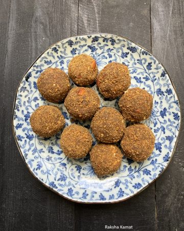 Round moong dal ladoos garnished with crushed cashews and almonds on a plate
