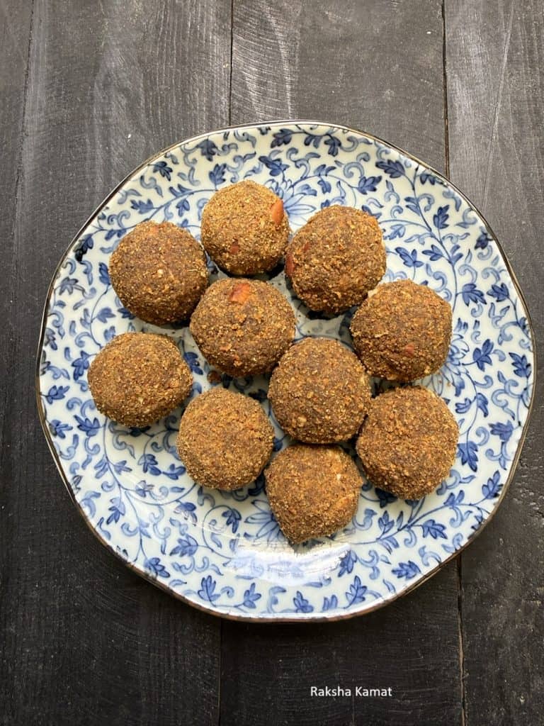 Round moong dal ladoos garnished with crushed cashews and almonds on a plate